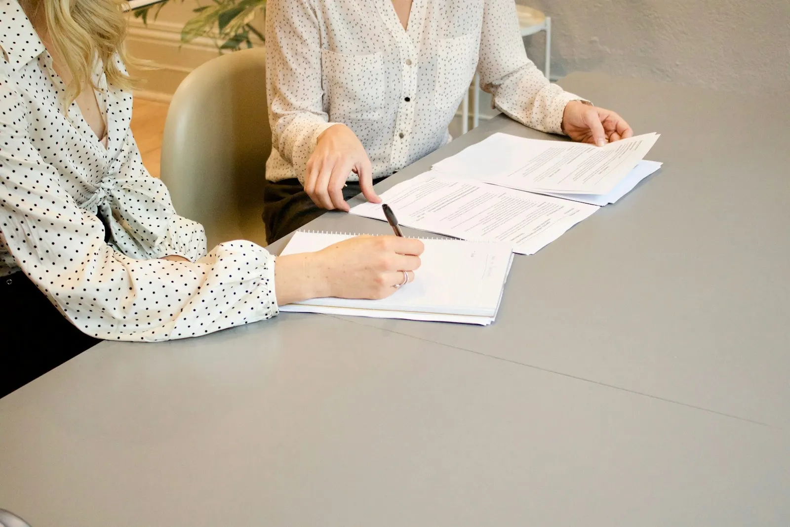Two people at a table going over paperwork and signing a document together